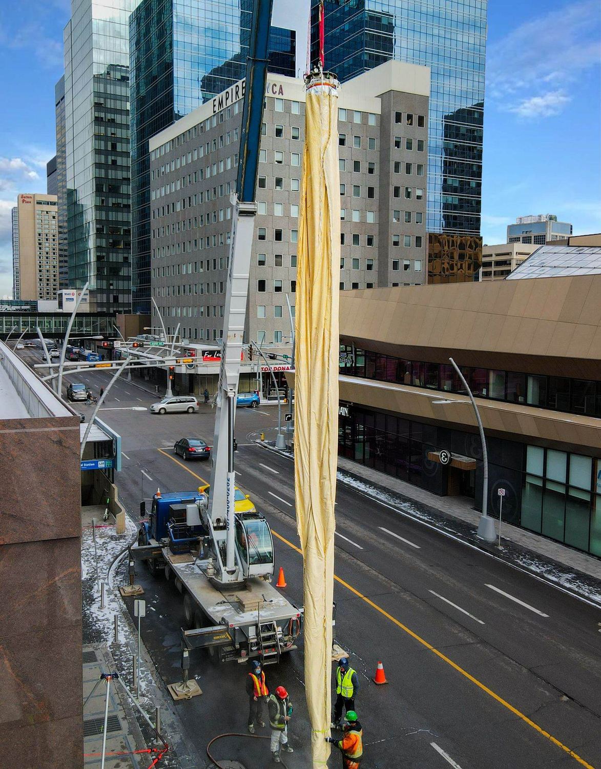 A full-length Triplex Liner lifted by crane over a downtown street before it is lowered into the structure