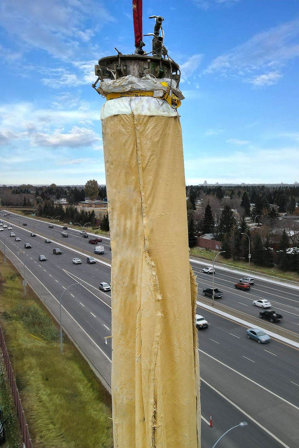 A giant Triplex Liner hanging from a crane above a live highway