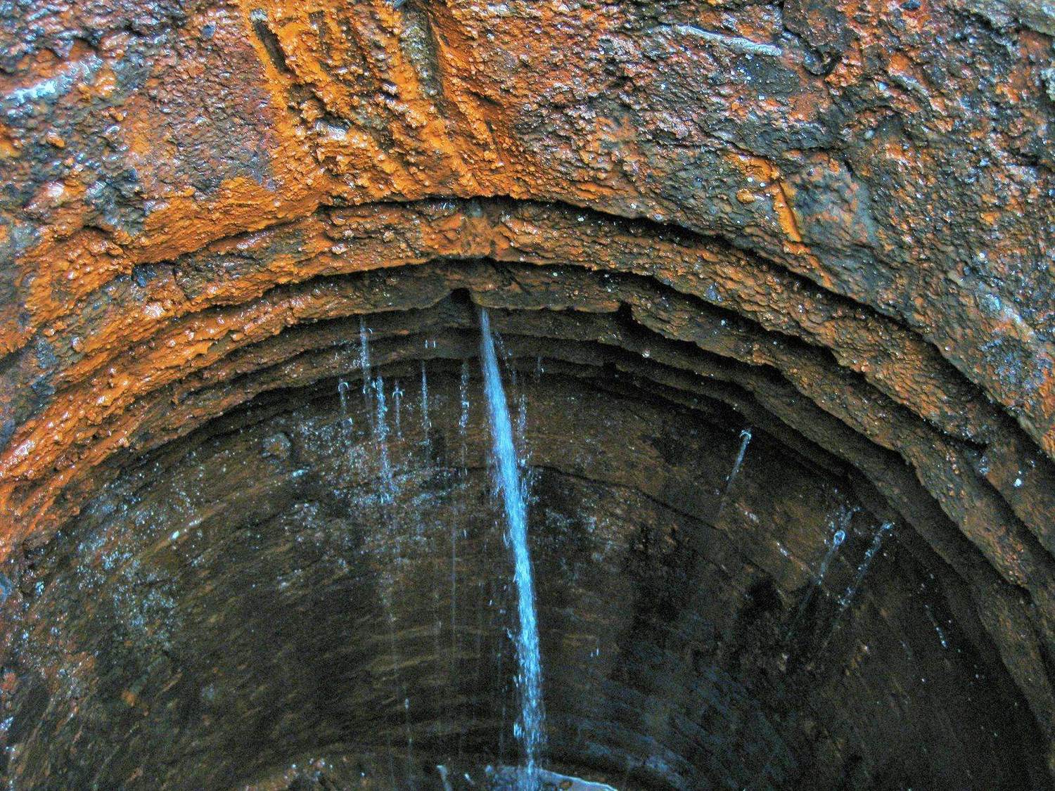 Groundwater infiltration running down the corroded wall of a sewer manhole
