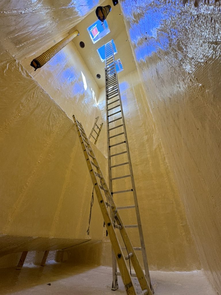 The lift station after lining, the full height of the wall in finished fiberglass, with an extension ladder for scale